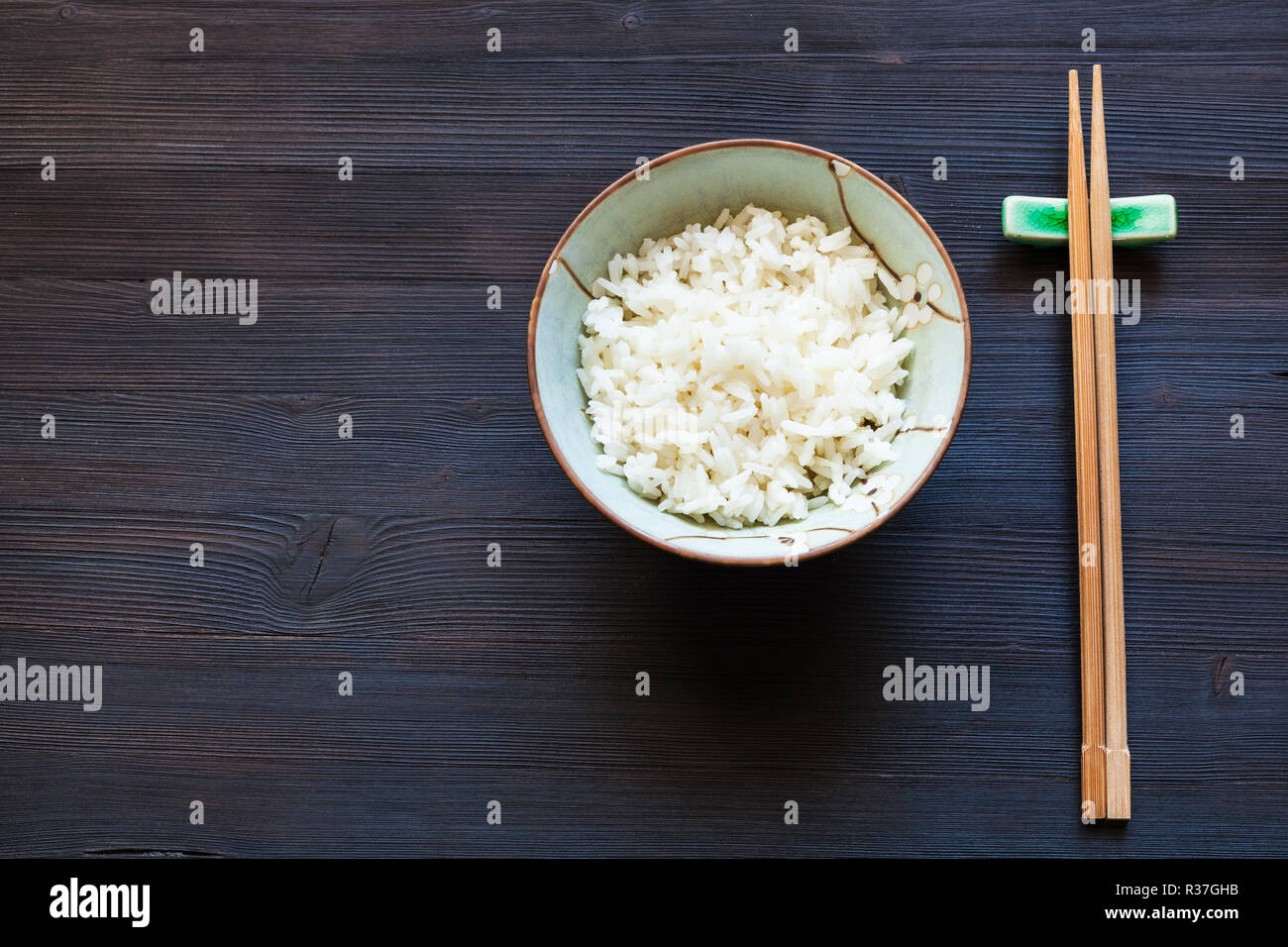 Vista dall'alto di una porzione di riso bollito in coppa e bacchette sul  resto sul tavolo scuro con copyspace Foto stock - Alamy