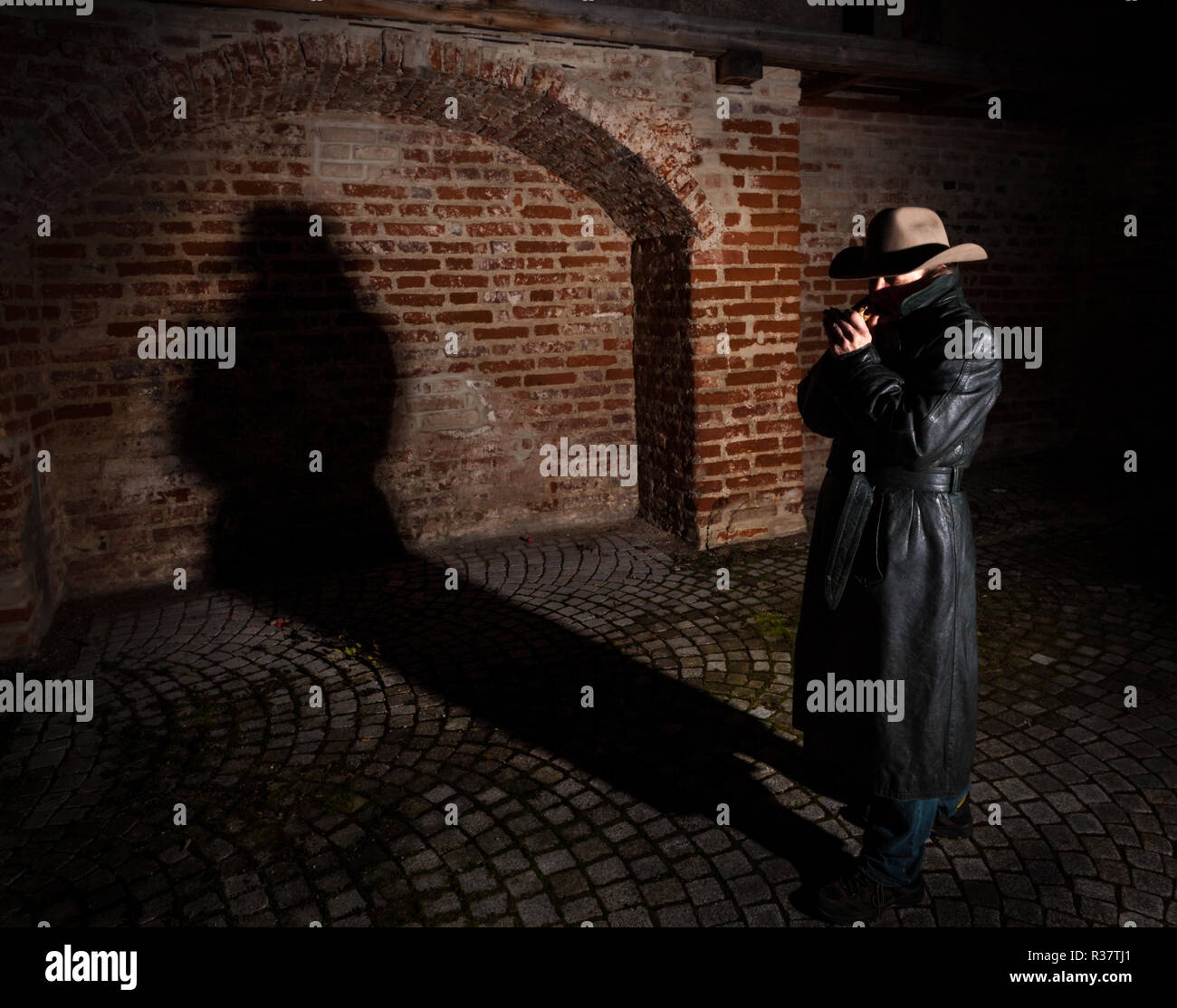L'uomo con il cappello e il cappotto di pelle, shadow nel retro, night shot, Germania Foto Stock
