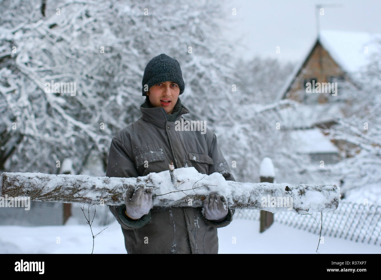 Giovani lumberjack è azienda big tagliò sul registro di giornata invernale nel bosco innevato Foto Stock