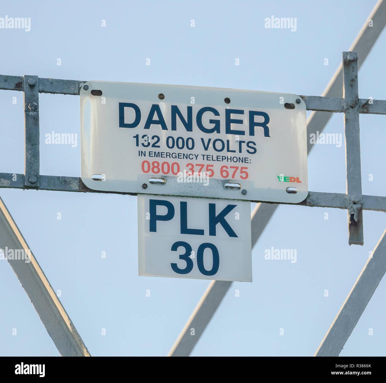 Un segnale di avvertimento su un traliccio di elettricità Foto Stock