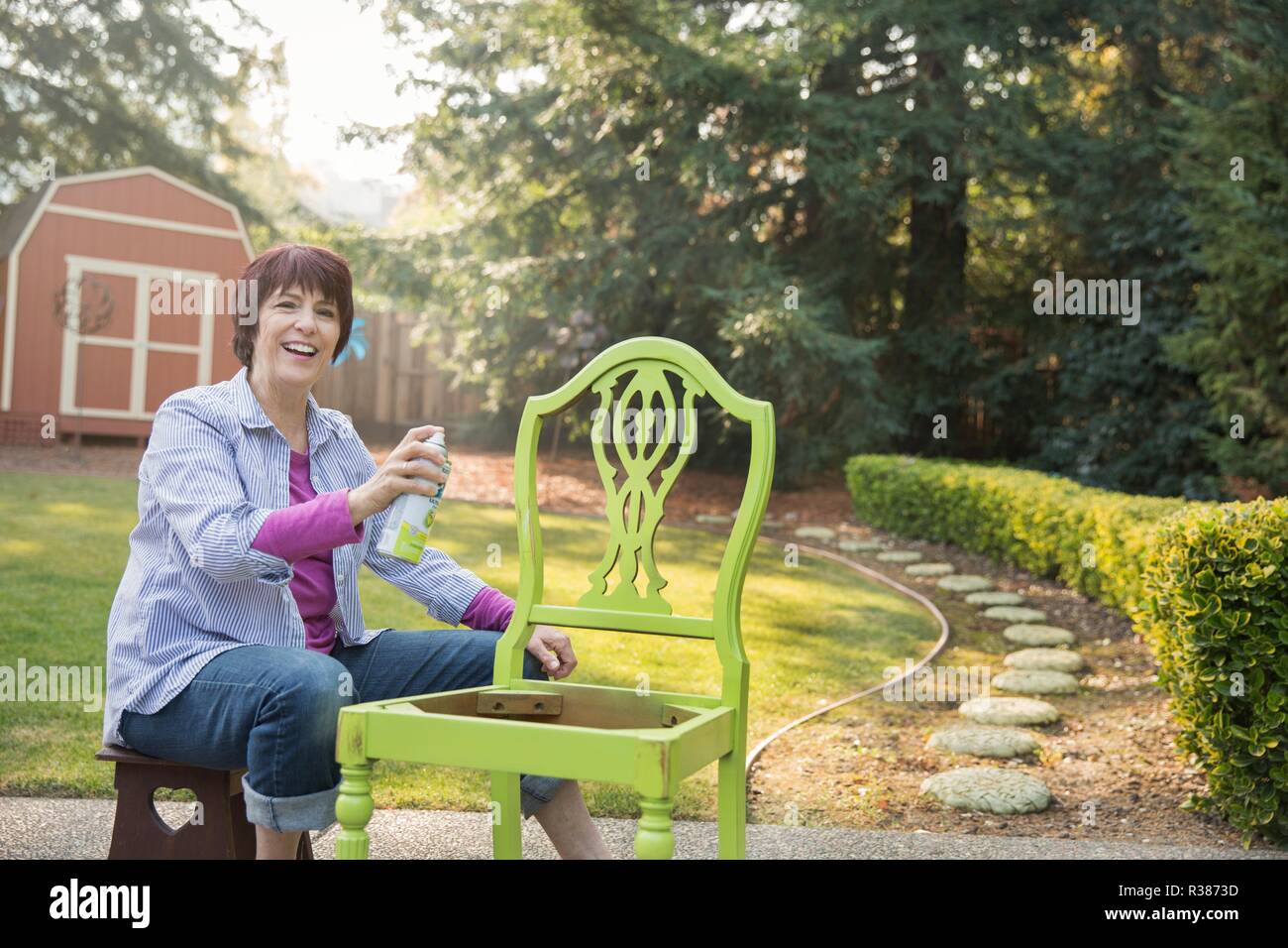 Un maturo donne artista il ripristino di una sedia. Foto Stock