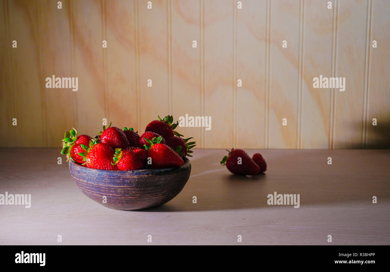 Fresas rojas maduras y frescas sobre vasija de greda Foto Stock