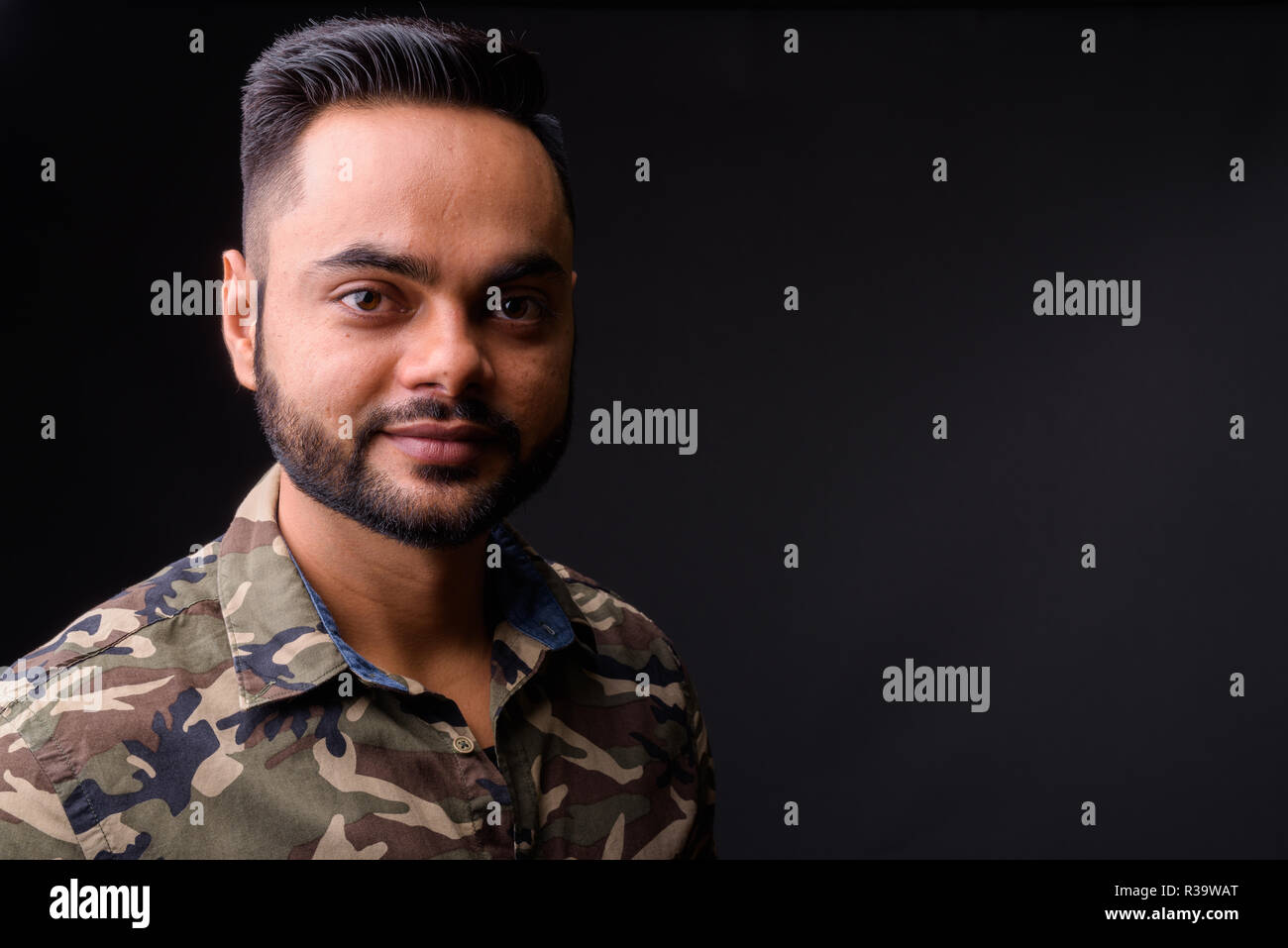 Giovani indiani barbuto uomo contro uno sfondo grigio Foto Stock