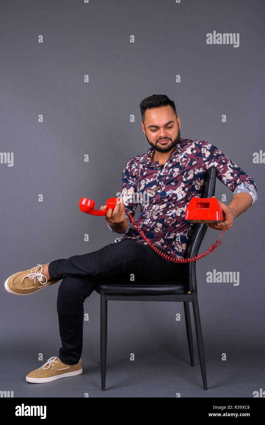 Giovani indiani barbuto uomo contro uno sfondo grigio Foto Stock