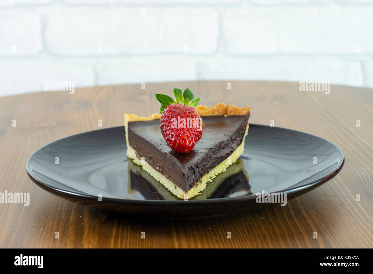 Freschi di forno torta al cioccolato con fragole e servite con la piastra nera sul legno Foto Stock