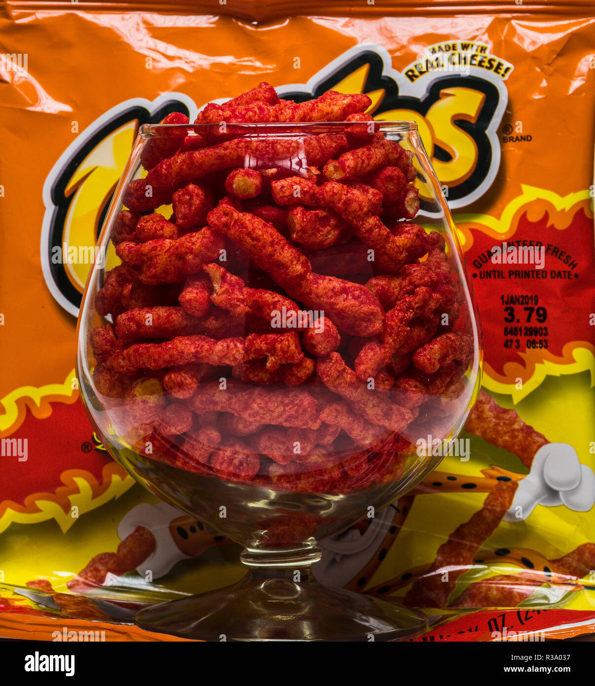 Flamin' hot cheetos nel bicchiere di brandy con sacco Foto Stock