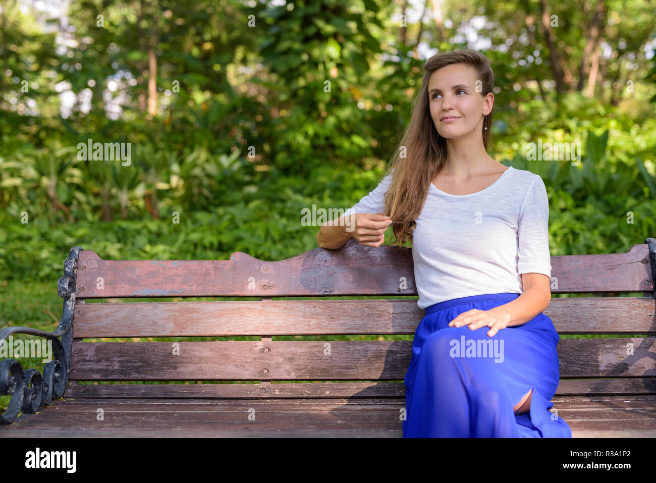 Bella donna pensare mentre si tocca i suoi capelli e sedersi sul Foto Stock