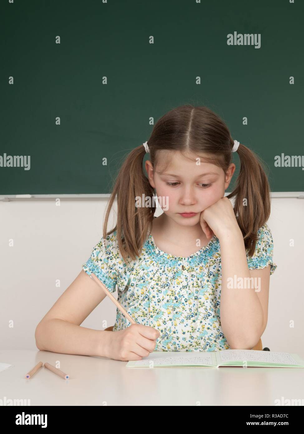 Schoolgirl seduti a tavola a scuola Foto Stock