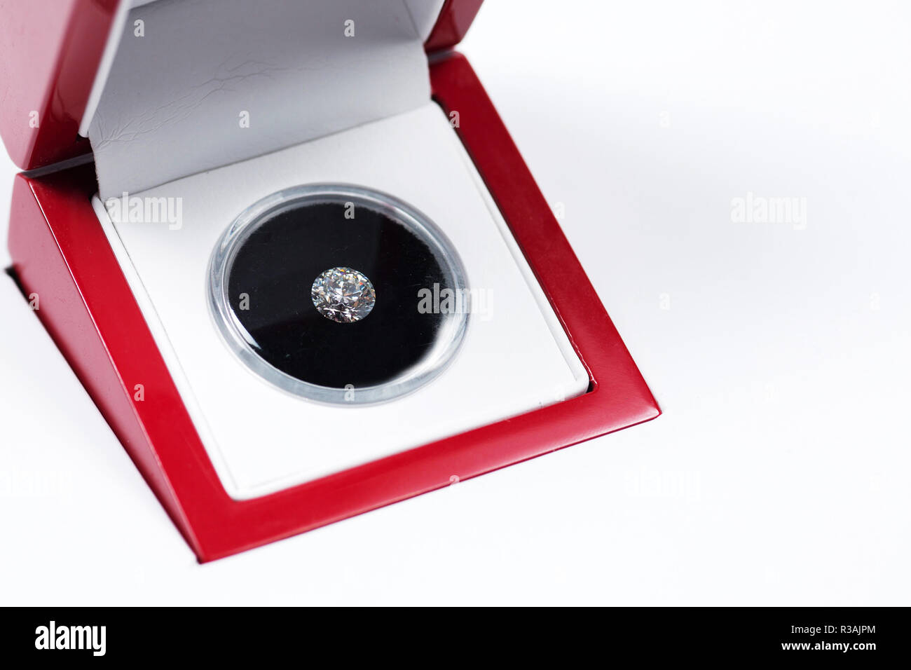 Diamante allentato in caso rosso, interni bianchi, feltro nero, isolato su bianco con spazio Copia a destra Foto Stock