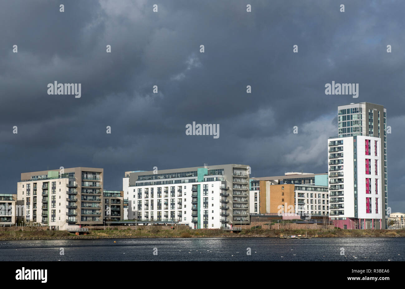 Cardiff Bay Appartamenti sotto tardi afternnon luce solare, con un colore scuro e minaccioso alle spalle di sky. Illuminazione perfetta per questo tipo di fotografia. Foto Stock