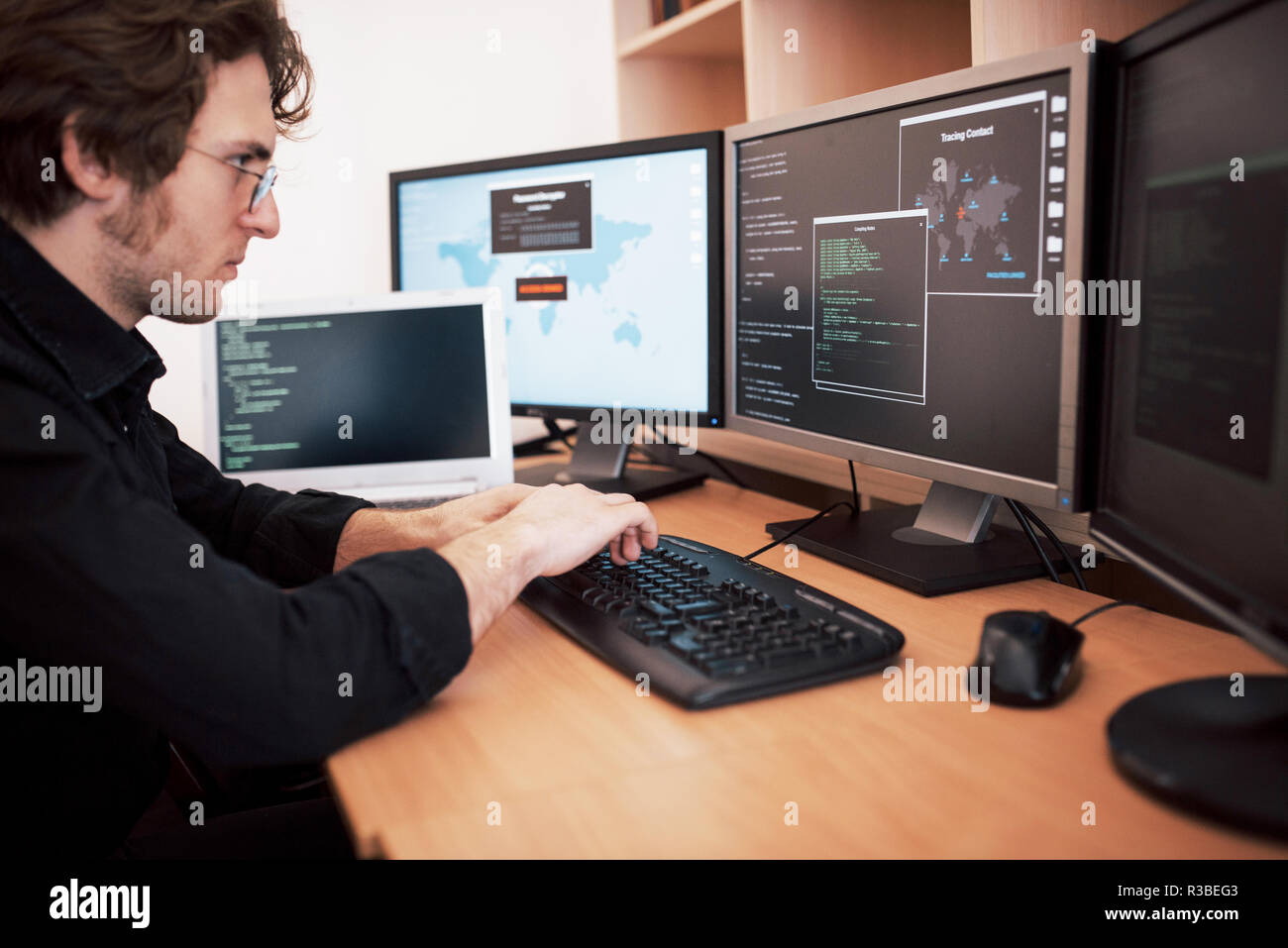 Programmatore maschio lavora su computer desktop con molti monitor in ufficio a sviluppare software company. Sito web design e programmazione tecnologie di codifica Foto Stock