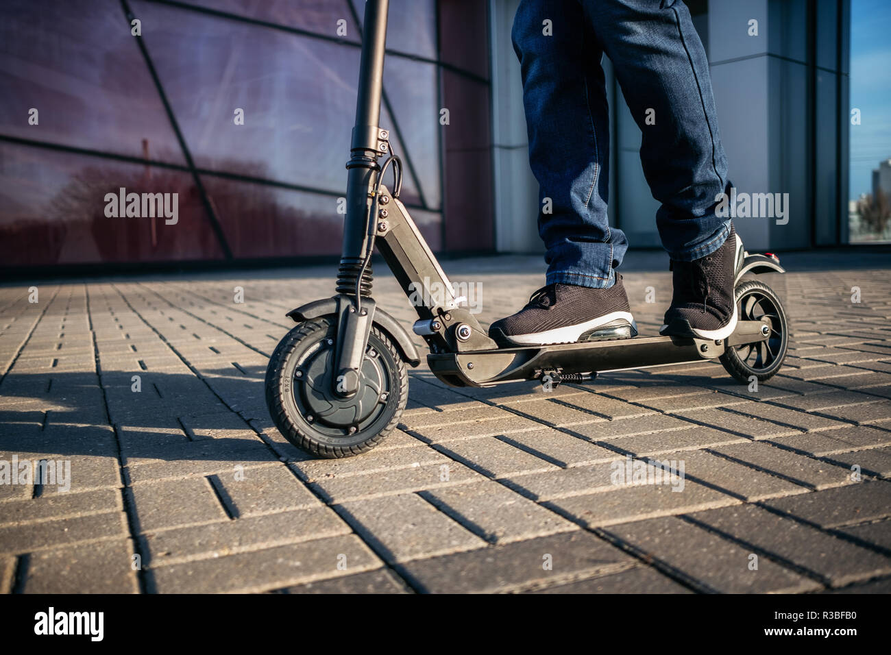 Vista ravvicinata di gambe di uomo su scooter elettrico all'esterno. Foto Stock