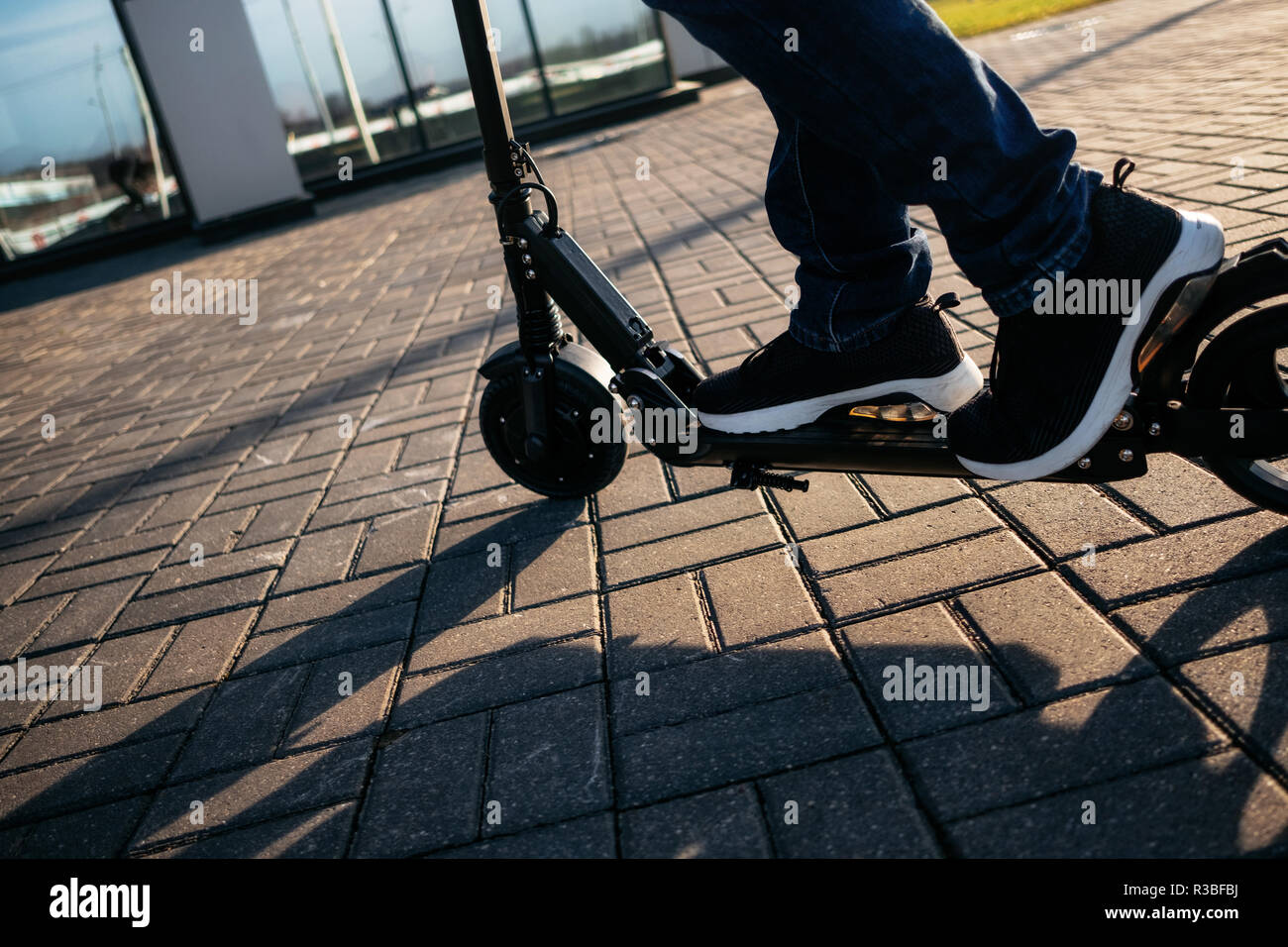 Vista ravvicinata di gambe di uomo su scooter elettrico all'esterno. Foto Stock