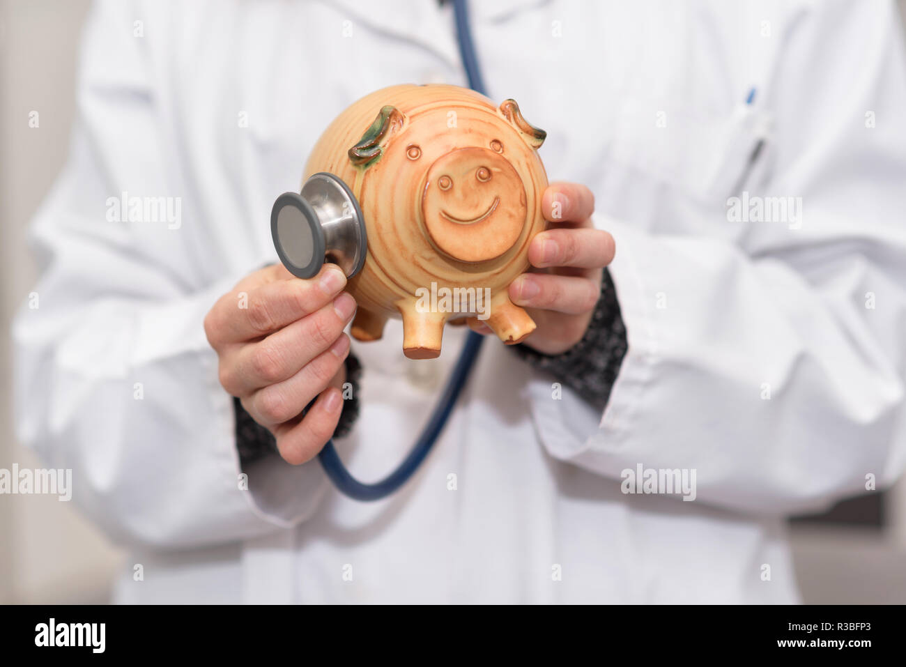 Medico tenendo salvadanaio close up. Assicurazione medica e sanitaria concetto di denaro. Foto Stock