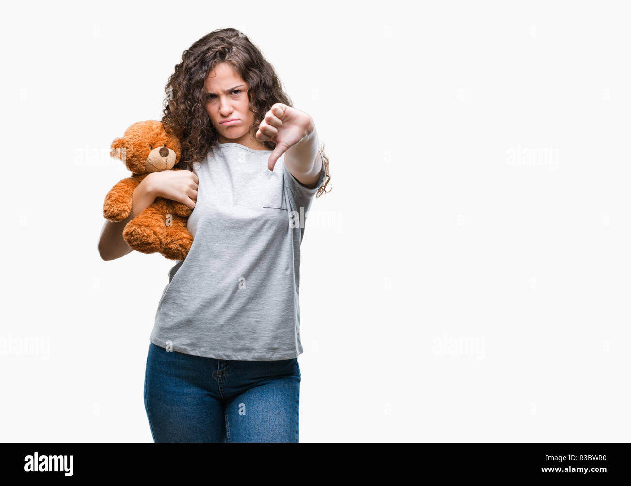 Bruna giovane ragazza con Teddy bear su sfondo isolato con volto arrabbiato, segno negativo che mostra antipatia con il pollice verso il basso, il concetto di rifiuto Foto Stock