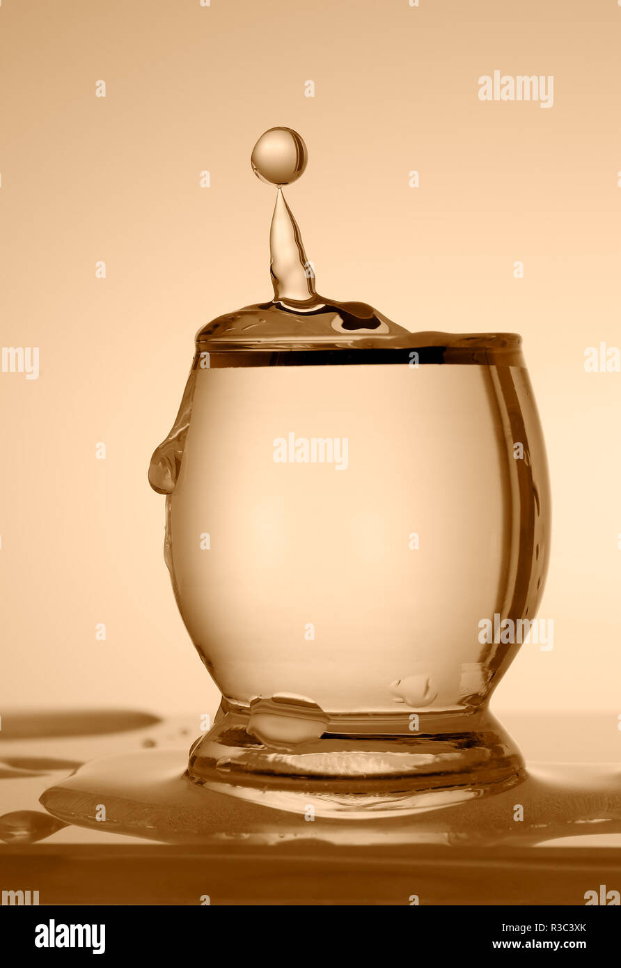 Goccia di acqua che cade in vetro. Foto in tonalità seppia. Foto Stock