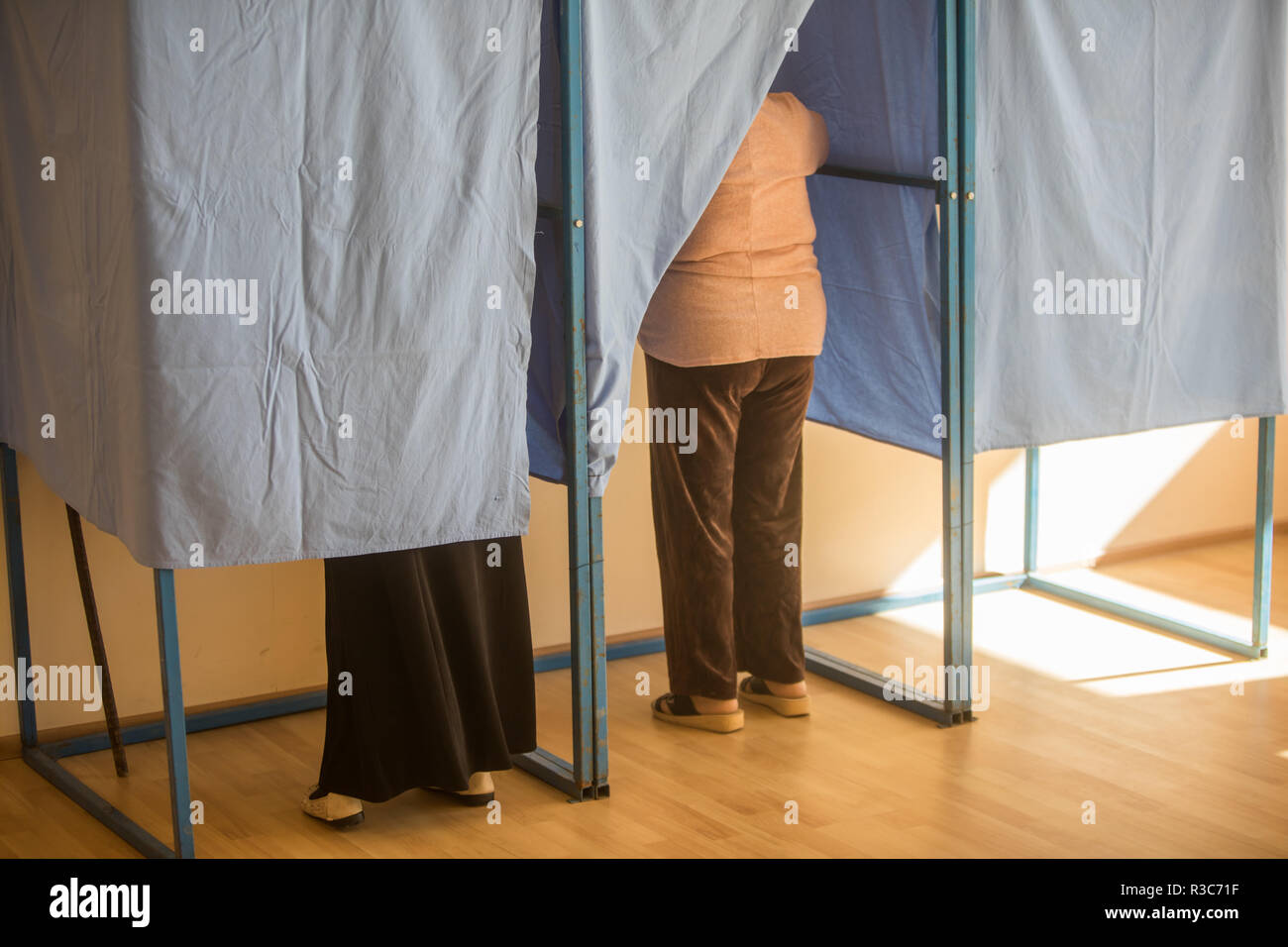 Immagine a colori di persone non identificabili voto in capanne in corrispondenza di una stazione di polling, durante le elezioni. Foto Stock