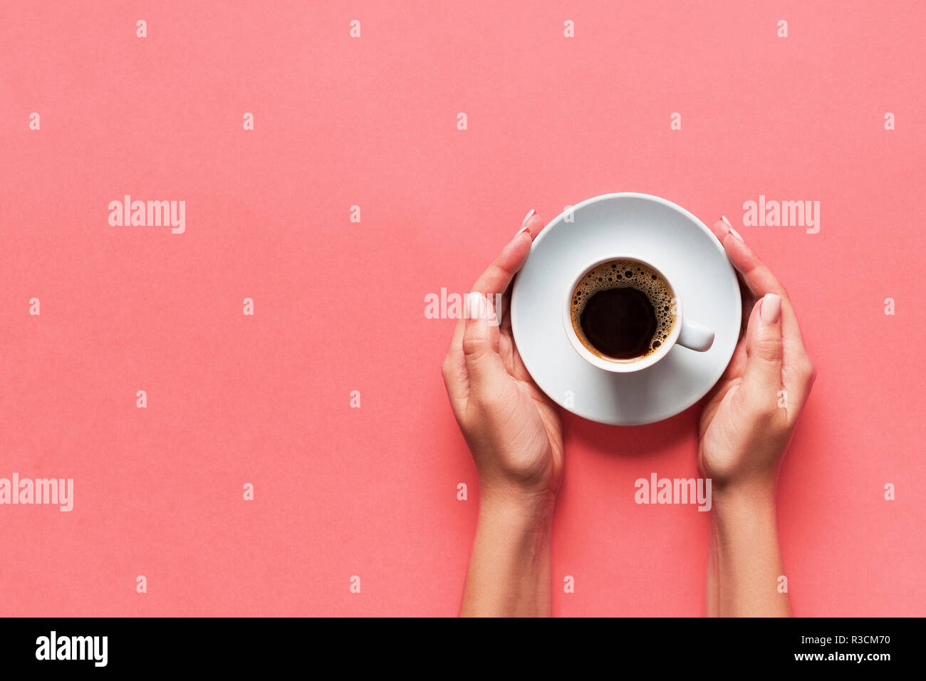 Stile minimalista donna mano che regge una tazza di caffè su sfondo rosa. Appartamento laico, vista dall'alto. Foto Stock