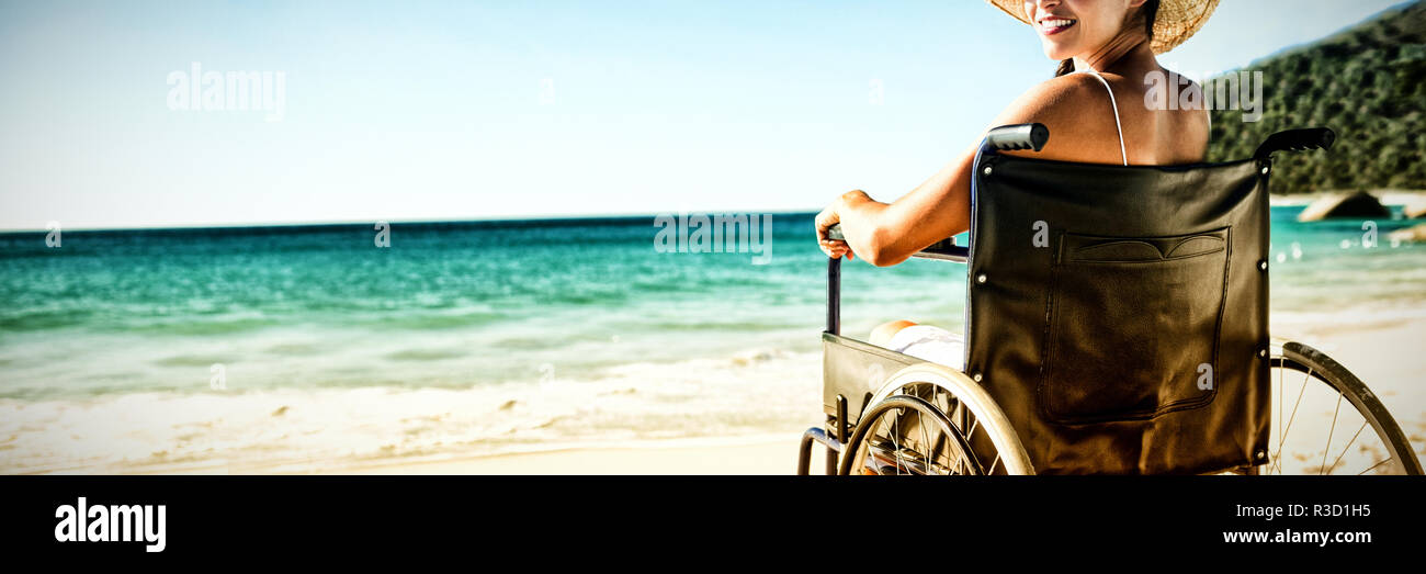 Sedia a rotelle donna seduta sorridente in telecamera Foto Stock