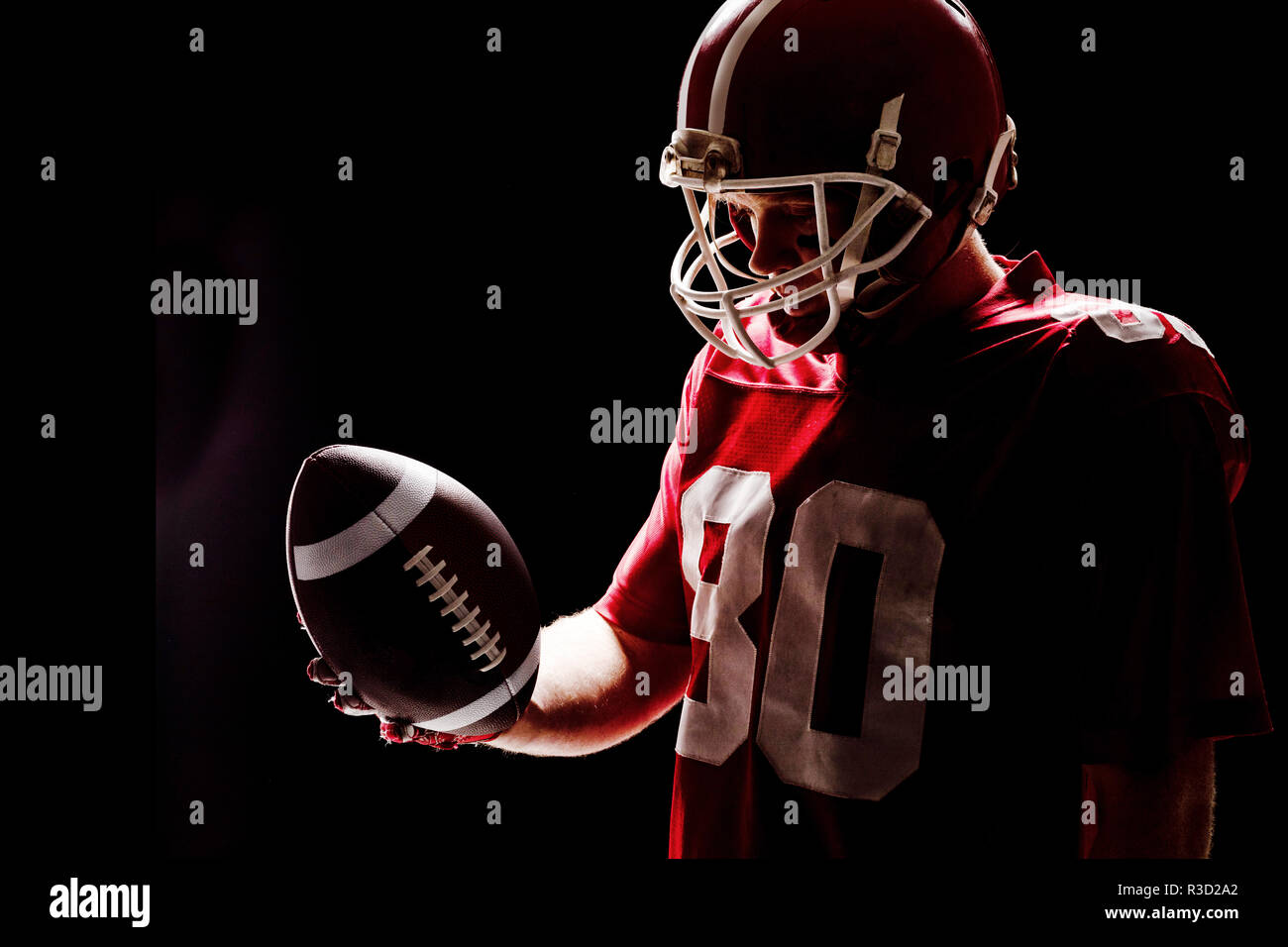 Giocatore di football americano con helmat guardando il pallone da rugby Foto Stock