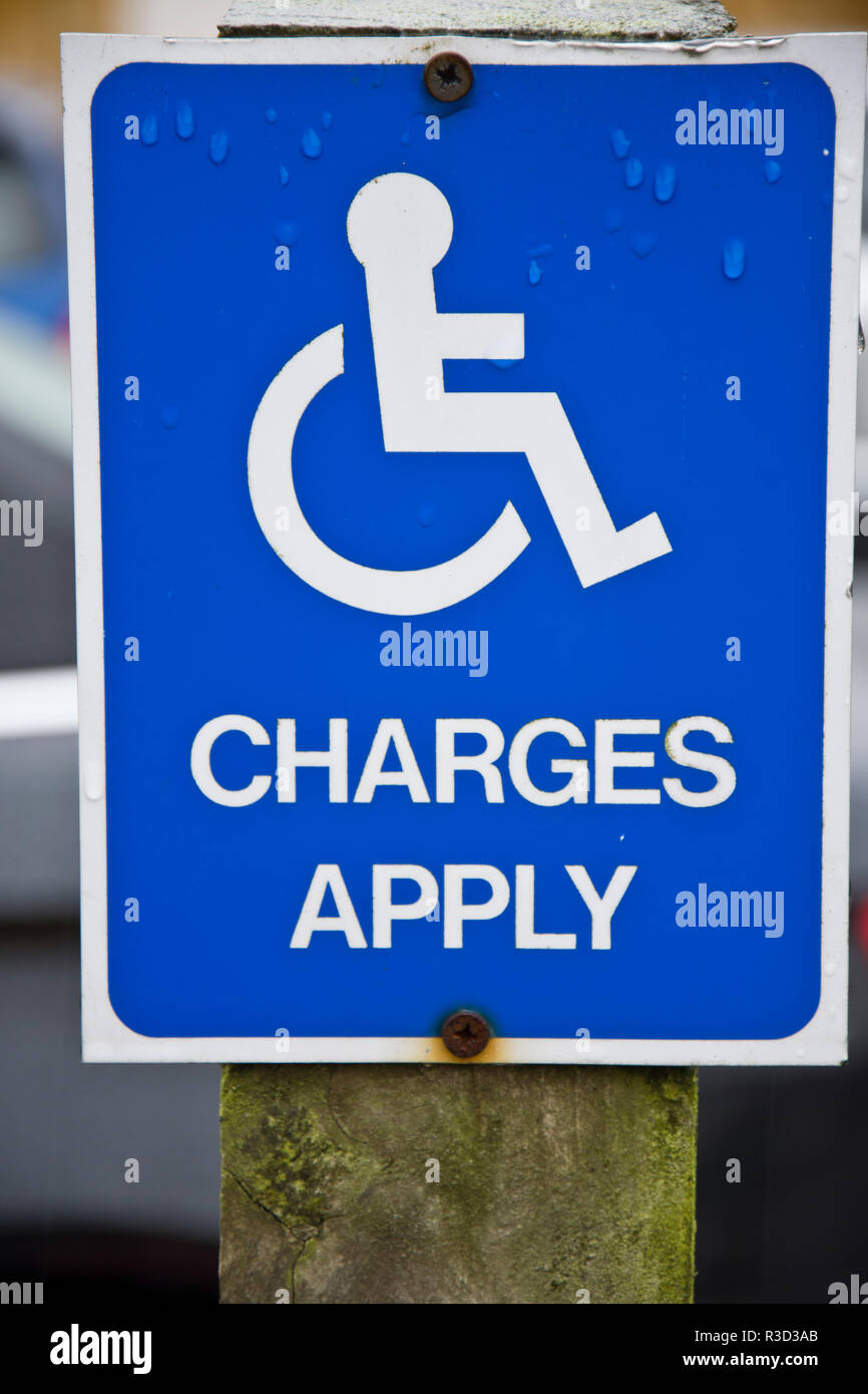 Segno che ricorda i guidatori disabili a pagare per il parcheggio auto. Foto Stock
