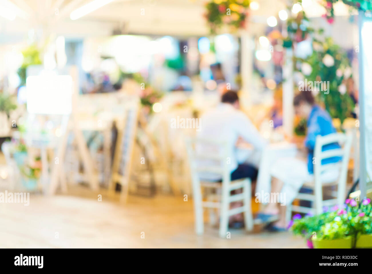 Sfocare lo sfondo della scena in un ristorante, offuscata irriconoscibile persone sedute al tavolo in giardino Foto Stock