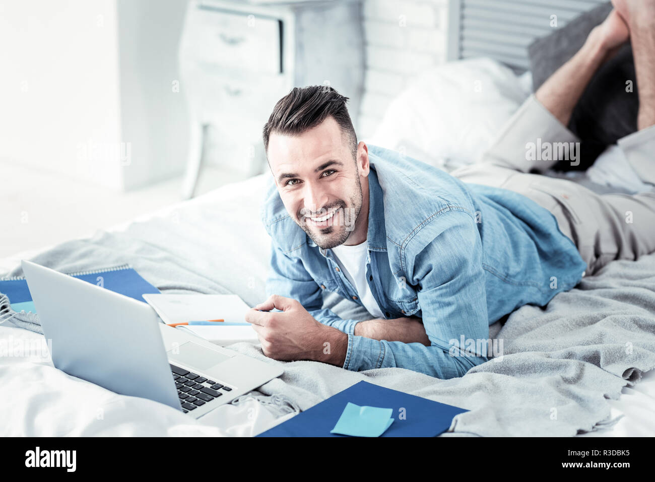 Express positività. Attraente giovane sensazione di felicità mentre giaceva sul letto e la testa di tornitura a fotocamera Foto Stock