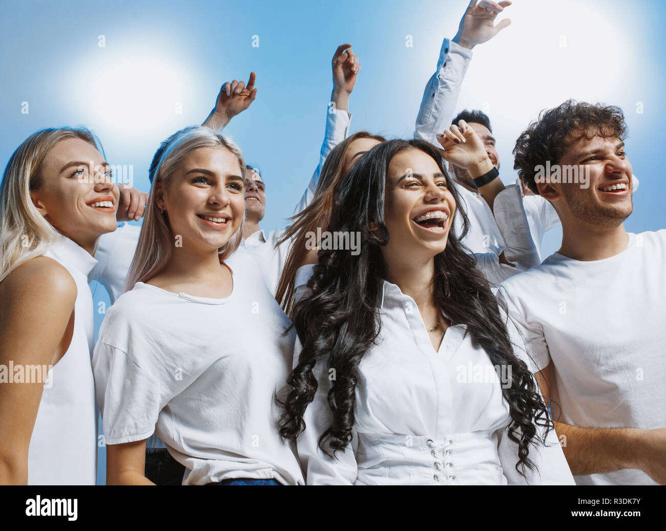 Il gruppo di allegro gioioso giovani in piedi e celebrando insieme oltre il blu di sfondo per studio Foto Stock