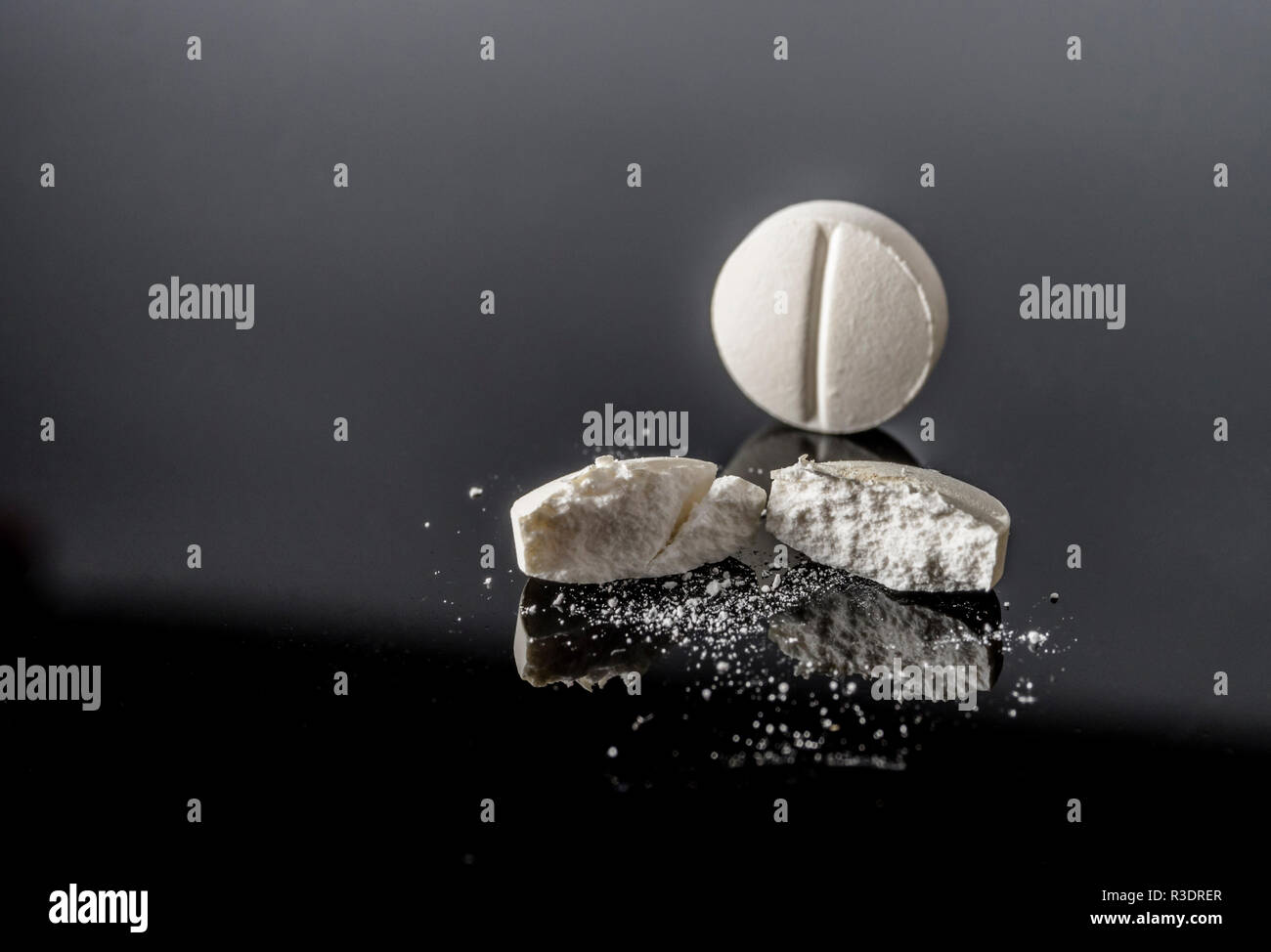 Pillola bianco da metà isolato in sfondo nero, immagine concettuale Foto Stock