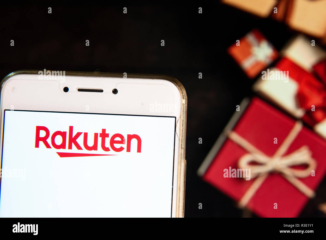 Giapponese del commercio elettronico e la società Internet Rakuten logo è visibile su un androide dispositivo mobile con un Natale regali avvolti in background. Foto Stock