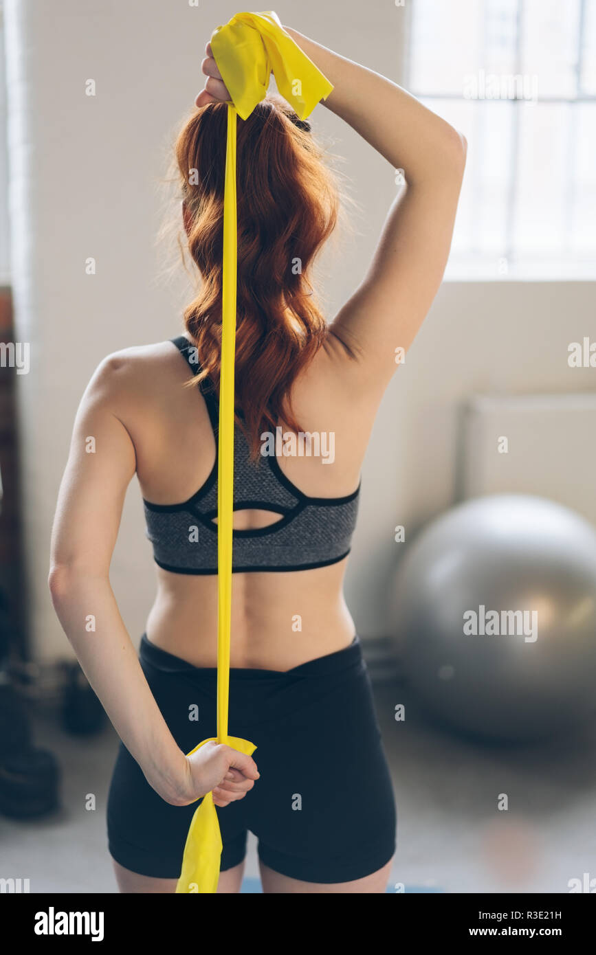 Giovane donna redhead emis sione di esercizio cinghie in una palestra per  allargare i suoi muscoli in una vista posteriore con la fascetta dietro la  schiena Foto stock - Alamy