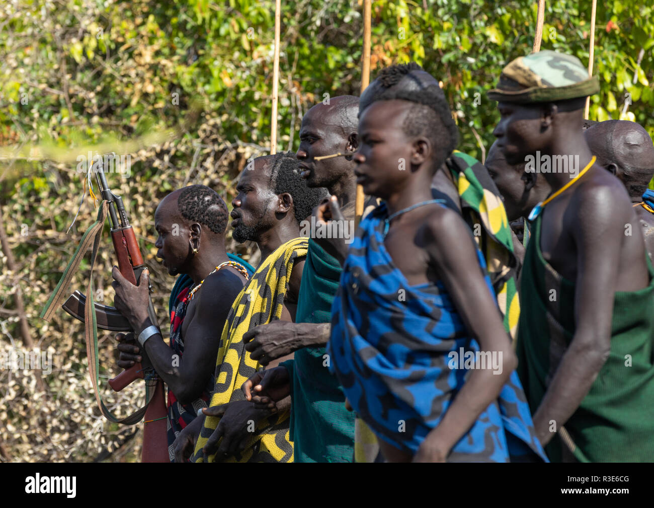 Suri tribe warriors sfilando prima un donga stick combattimenti rituali, valle dell'Omo, Kibish, Etiopia Foto Stock