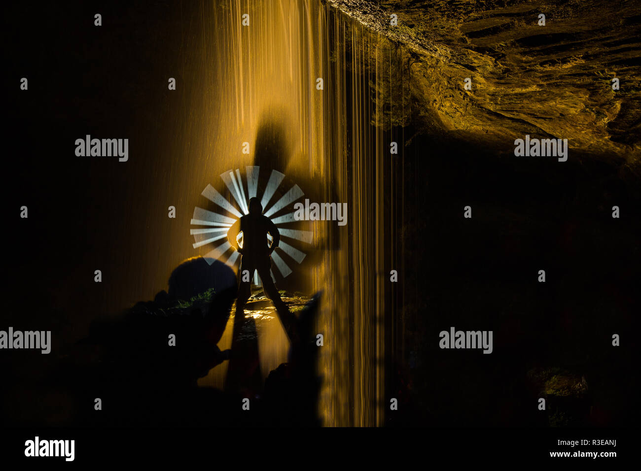 La fotografia notturna all'interno di una grotta con cascata e illuminato con lampioncini colorati per evidenziare la figura del modello. Foto Stock