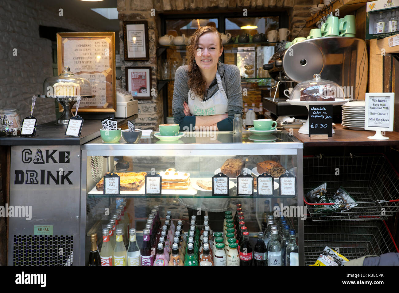 Un sorridente giovane donna lavoratrice che serve cibo e bevande nella contemporanea vecchio ufficio stampa cafe ristorante a Llandovery Wales UK KATHY DEWITT Foto Stock
