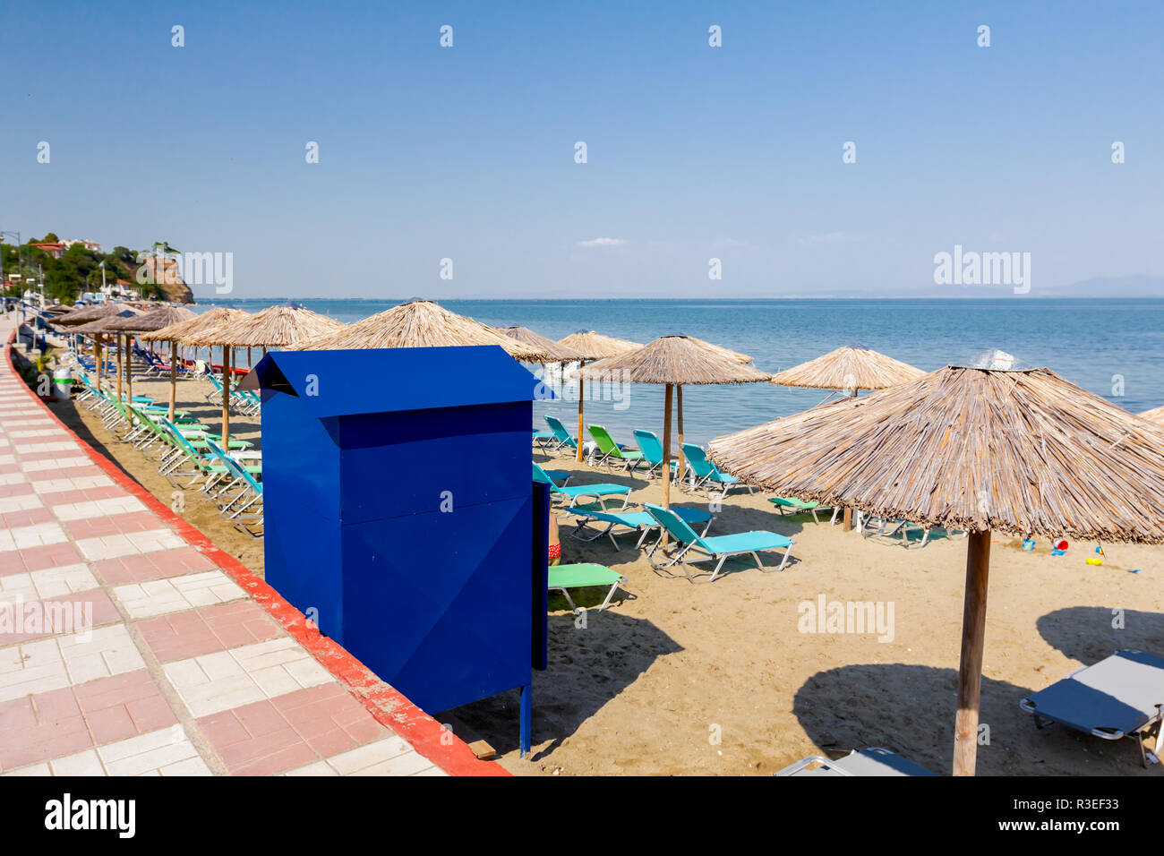 Blu di usura in metallo della cabina sulla spiaggia di sabbia fine  attrezzata con ombrelloni di paglia, ombrelloni e sedie a sdraio, i turisti  sono prossimi alla costa Foto stock - Alamy