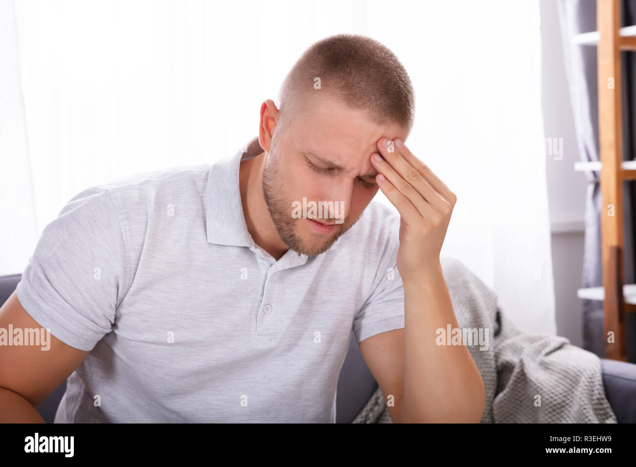 Ritratto di un giovane uomo che soffre di mal di testa a casa Foto Stock