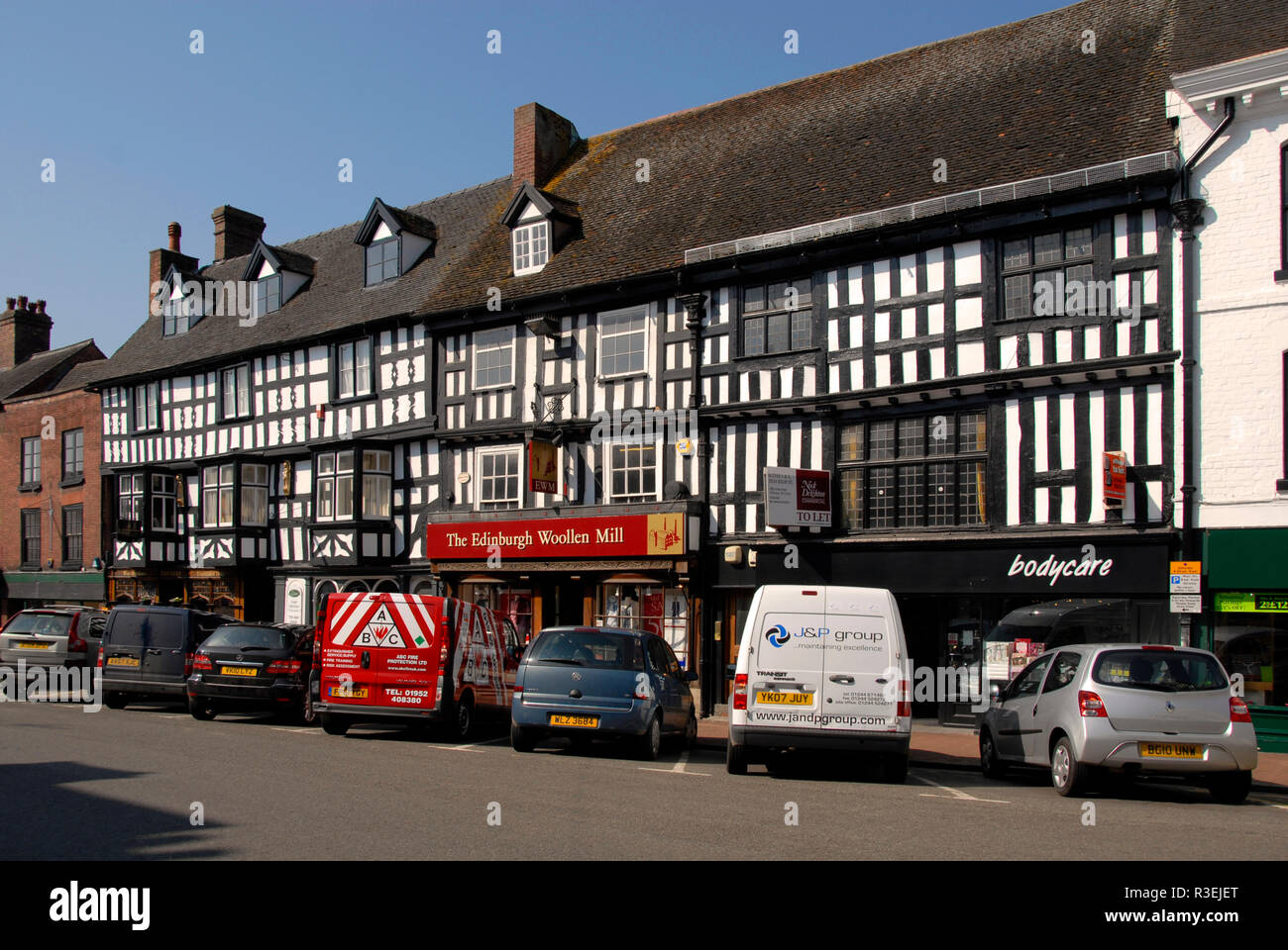 Fila di negozi, High Street, Bridgnorth, Shropshire, Inghilterra, con veicoli parcheggiati davanti Foto Stock