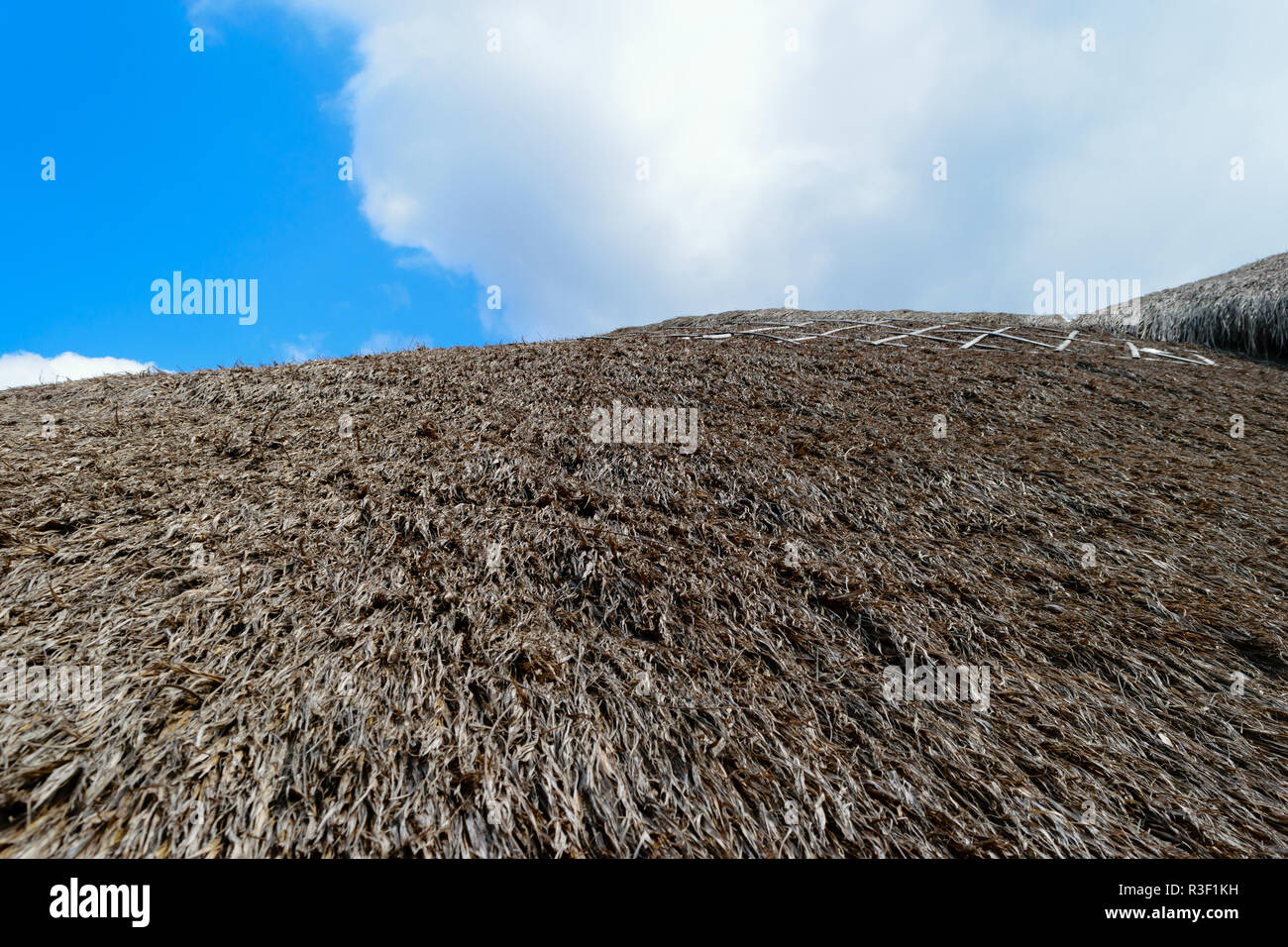 Superficie di sfondo del tetto di paglia davanti al cielo blu e nuvole bianche Foto Stock