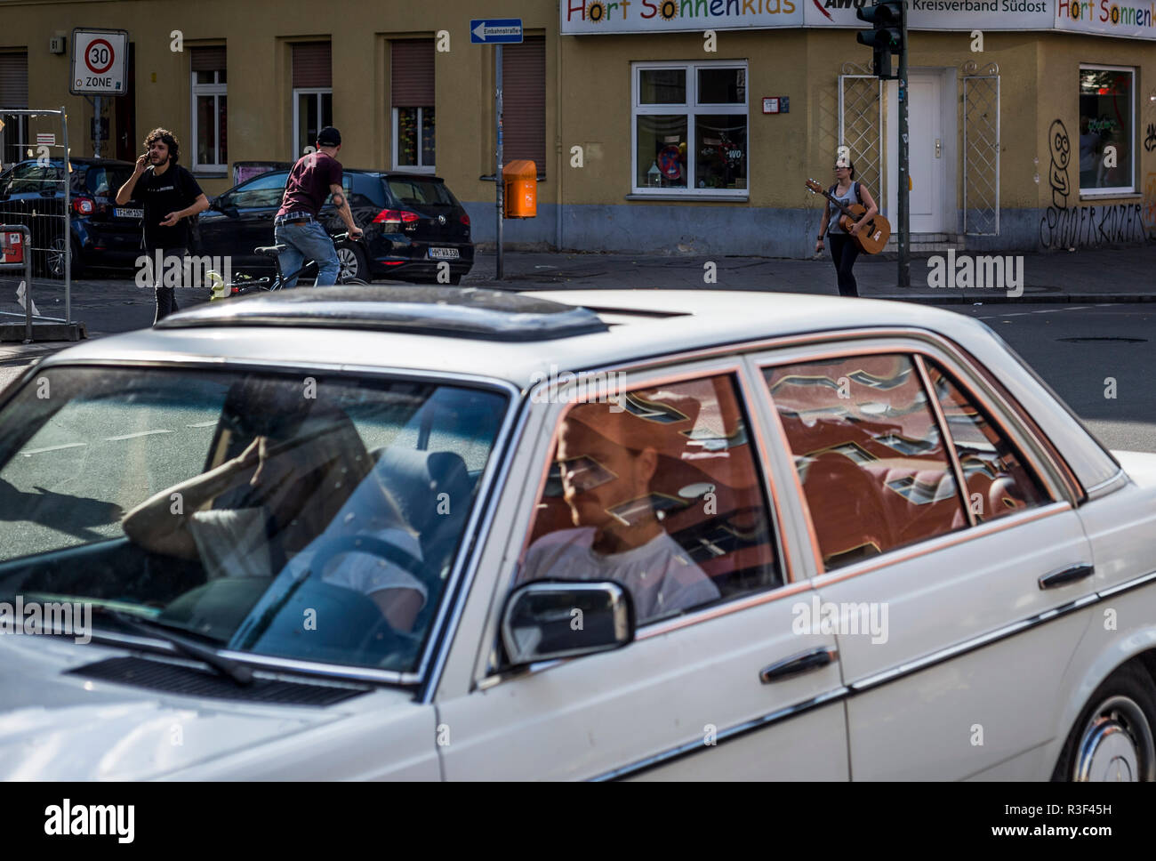 Una donna che porta una chitarra per le strade di Neukolln, Berlino, Germania. Foto Stock