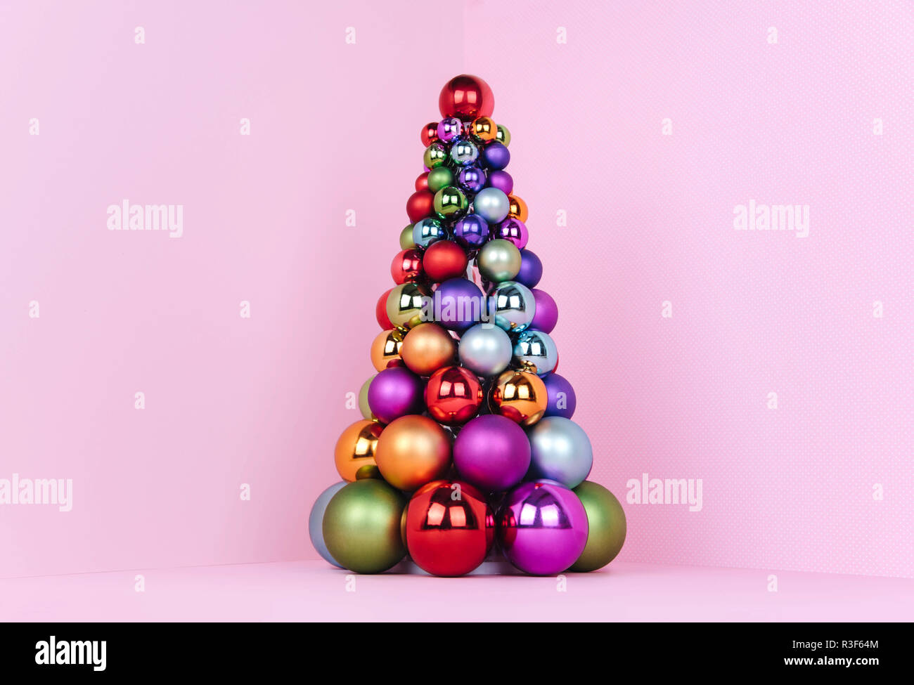 Albero di Natale fatto di decorazione a sfera su sfondo rosa. Foto Stock
