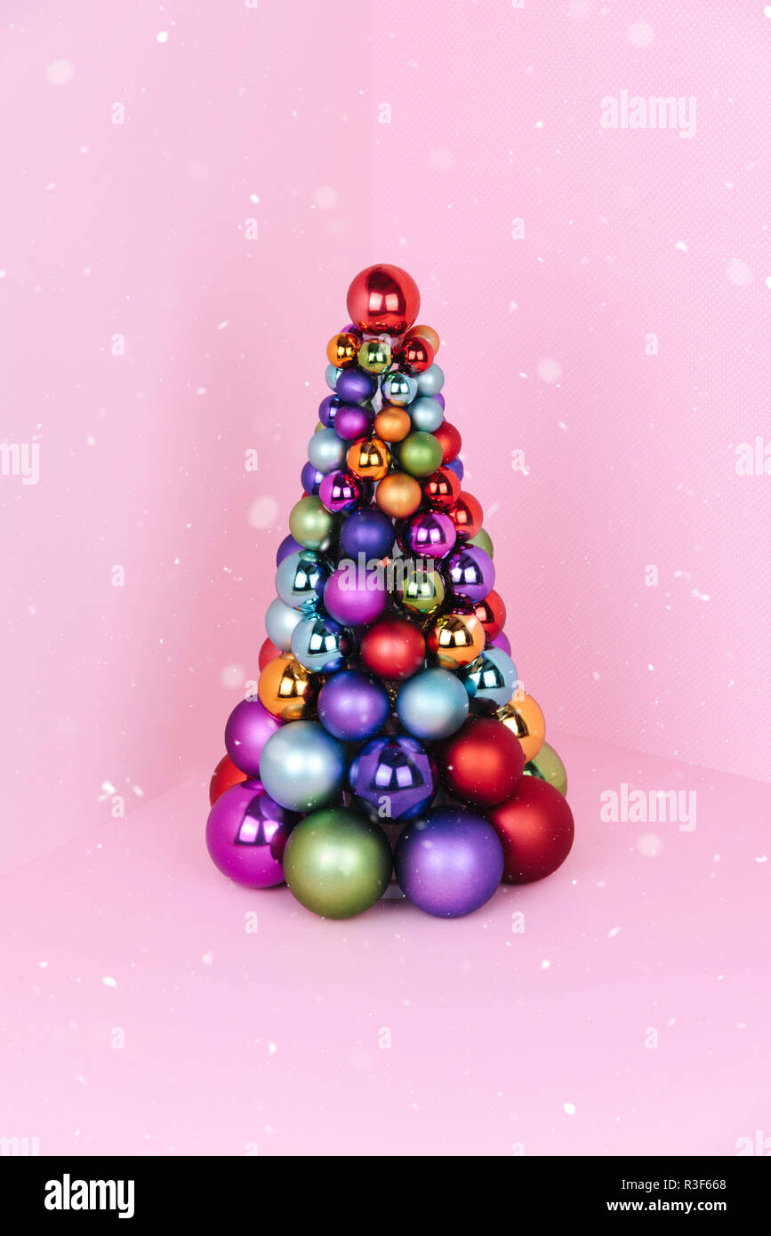 Albero di Natale fatto di decorazione a sfera su sfondo rosa. Foto Stock