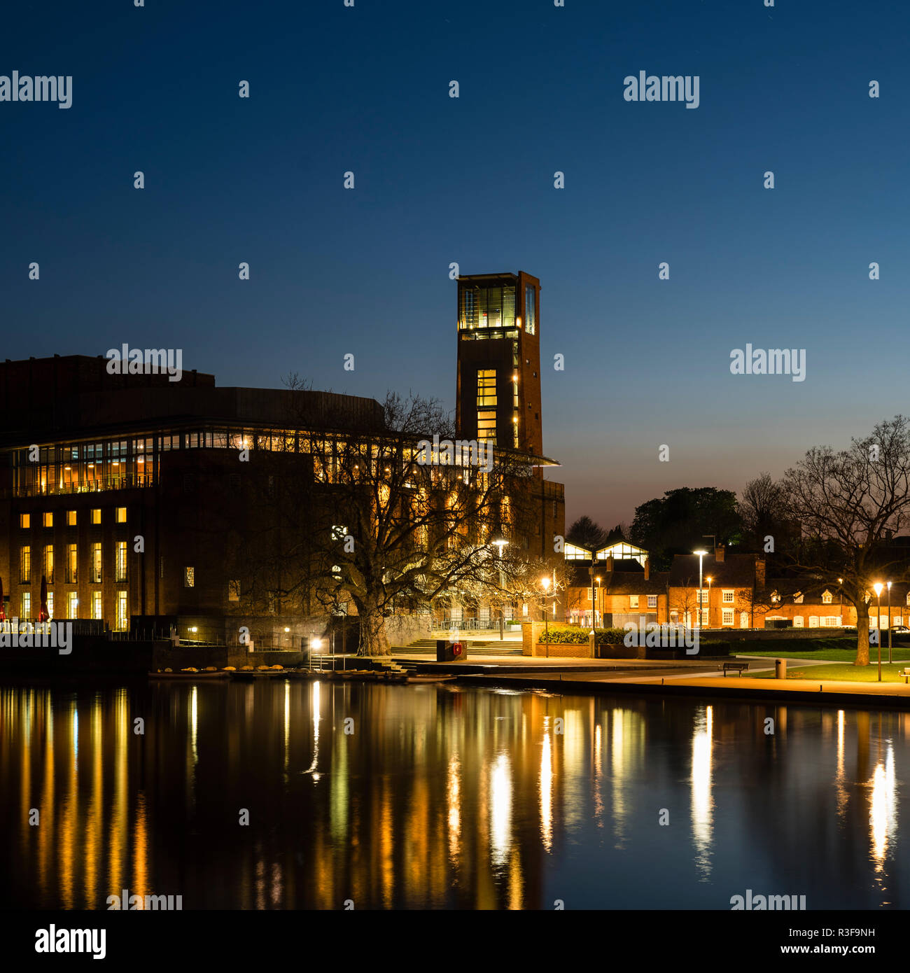 Il Royal Shakespeare Company teatro a Stratford-upon-Avon, Warwickshire, Regno Unito prese al tramonto con le luci luminose e riflessa nel fiume. Foto Stock