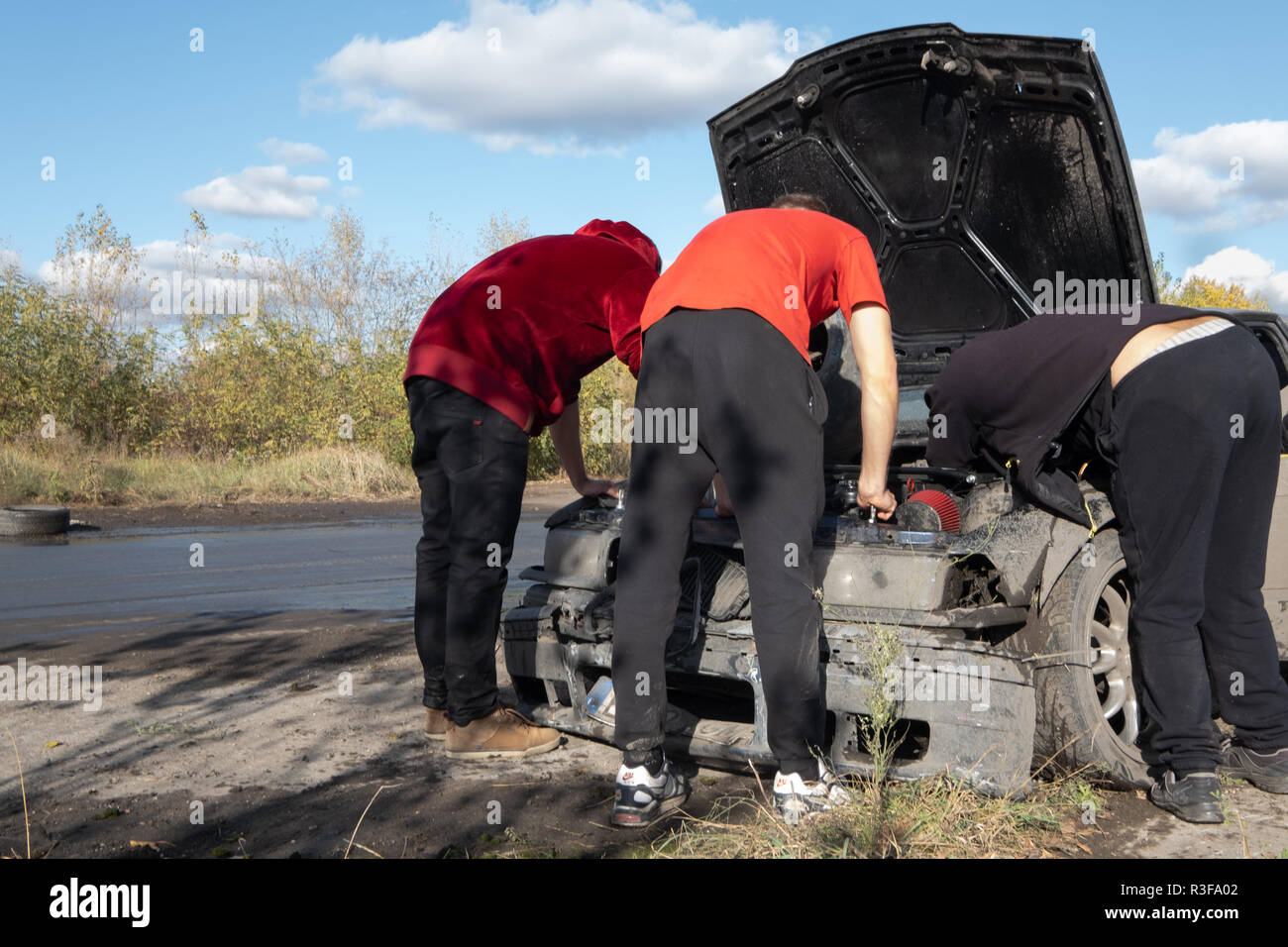 / Varsavia Polonia - Ottobre 21, 2018: 3 uomini riparazione auto danneggiata durante il drifting amatoriale evento in Ursus, abbandonata fabbrica del trattore nella periferia di Varsavia. Foto Stock