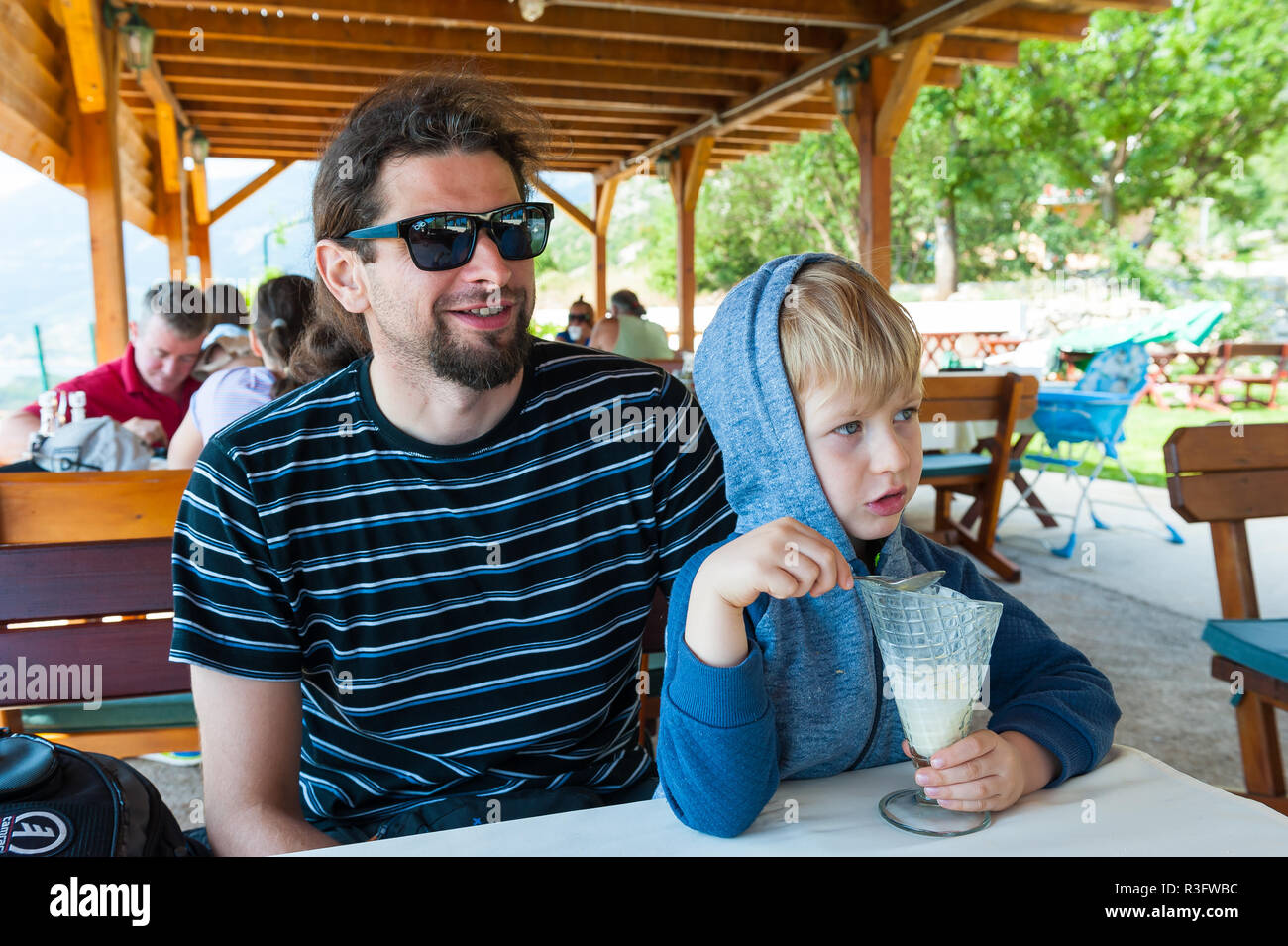 Quattro anni di vecchio ragazzo seduto accanto a suo padre e a mangiare il gelato in un ristorante in Montenegro Foto Stock