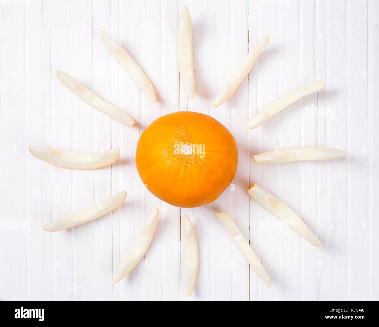 Melone giallo in forma di sun sul bianco sullo sfondo di legno Foto Stock