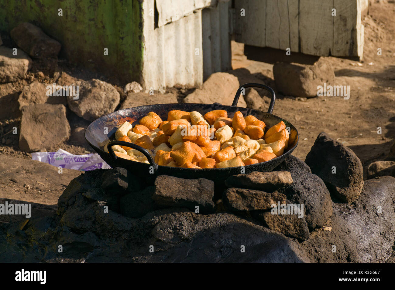 Mandazi, Swahili pane fritto snack, noto anche come dabo o Dahir, essendo cotti in un tegame grande su una pietra una buca per il fuoco in strada, Mathare, Kenya Foto Stock