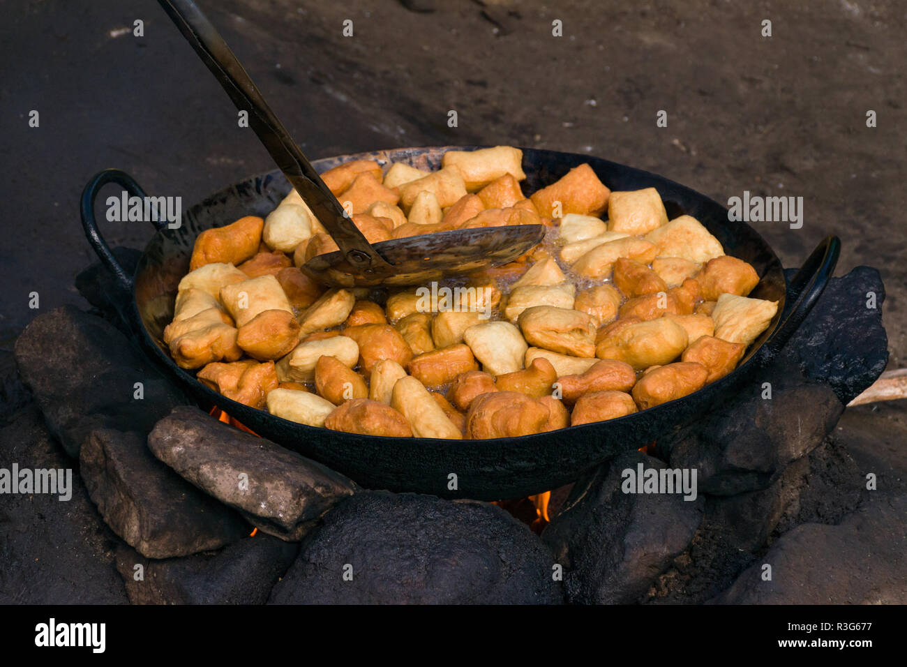 Mandazi, Swahili pane fritto snack, noto anche come dabo o Dahir, essendo cotti in un tegame grande su una pietra una buca per il fuoco in strada, Mathare, Kenya Foto Stock
