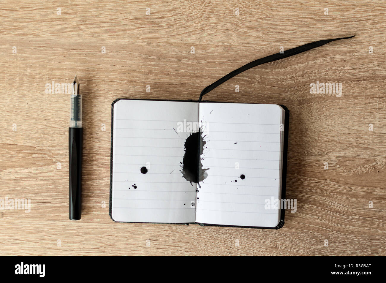 Penna stilografica su un notebook. Inchiostro nero splash. Un tavolo di legno. Copia dello spazio. Foto Stock
