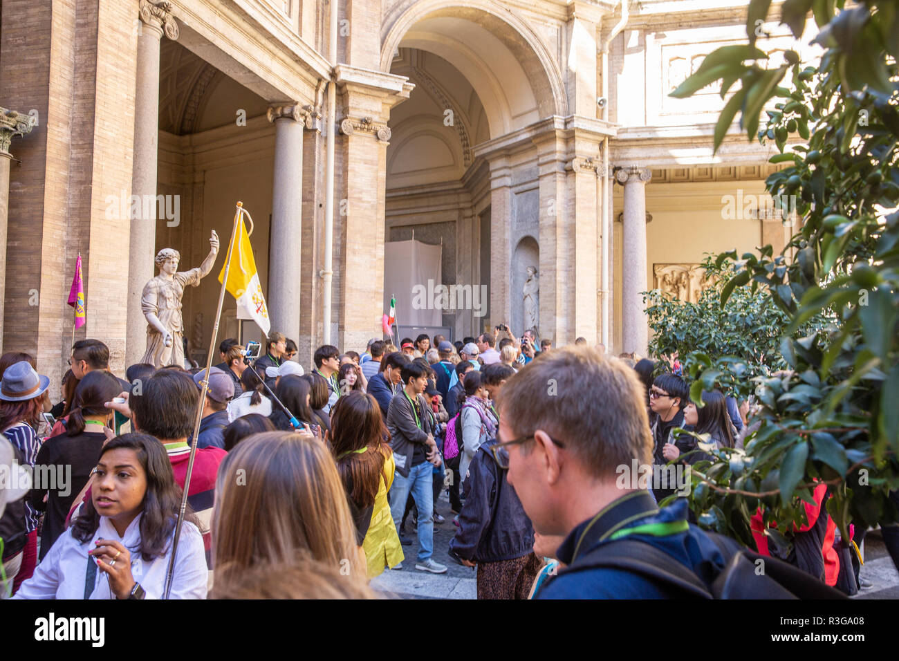 I turisti seguire il gruppo turistico leader portando una bandiera durante un tour del Vaticano a Roma,Italia Foto Stock