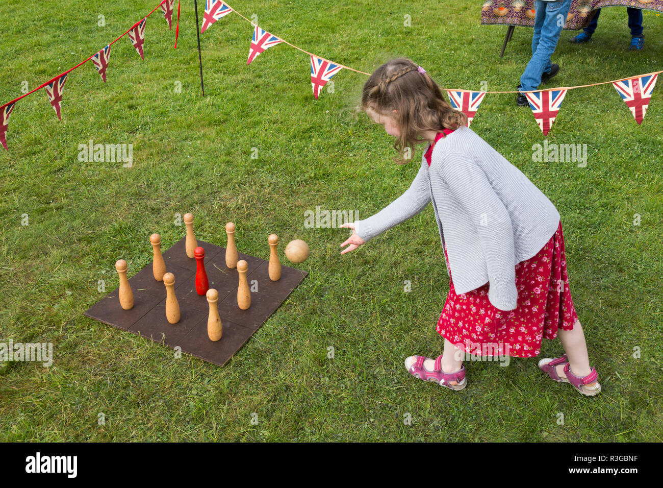 Un bambino di sei anni ragazza che gioca con un vecchio stile classico tradizionale serie di birilli su un consiglio di amministrazione che richiedono il lancio di una palla da parte dei giocatori. Regno Unito (98) Foto Stock